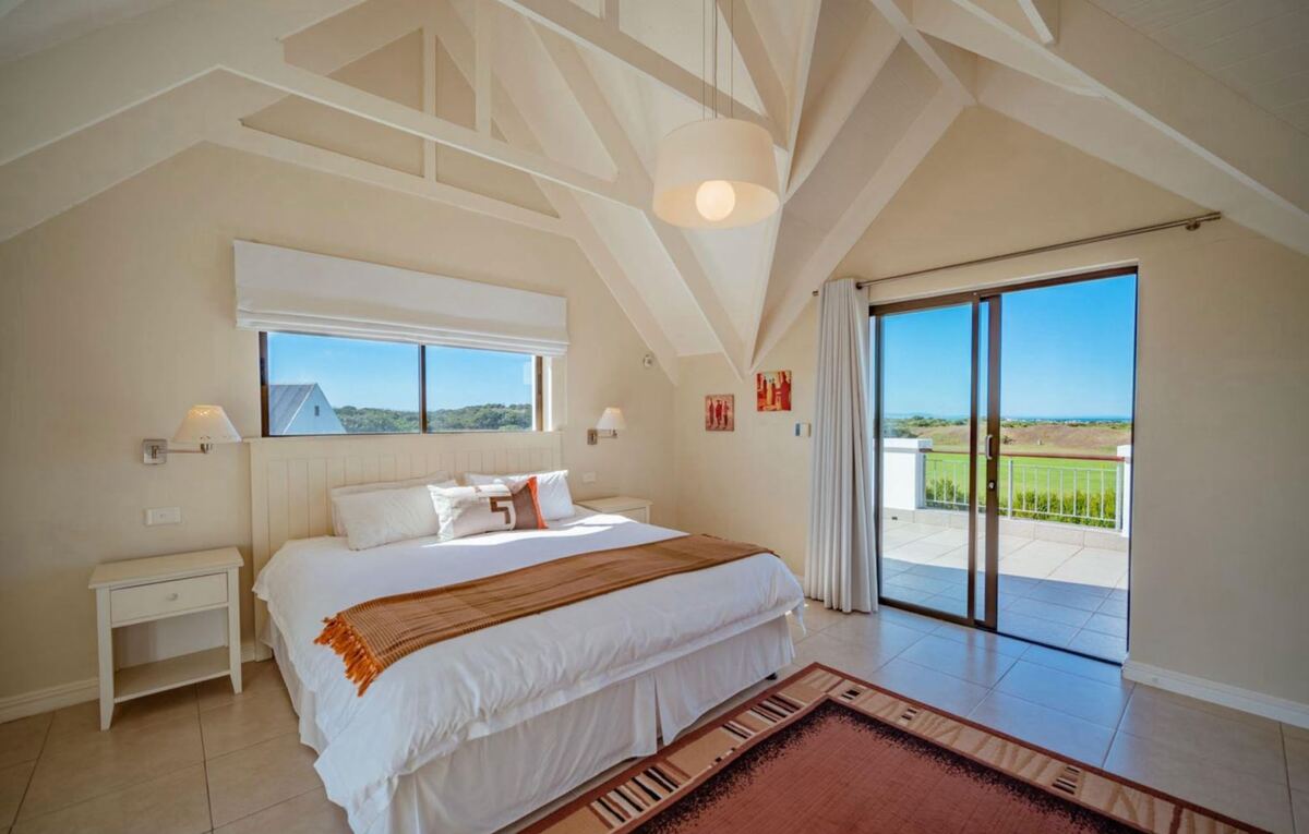 King bedroom with vaulted white ceiling and doors to the terrace